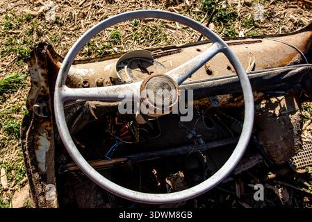 Volante di una vecchia auto distrutta e abbandonata in campagna volante con ruggine e pezzi di metallo a Valsanzibio Padova Veneto Italia Foto Stock