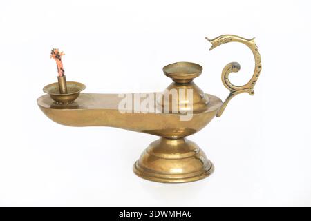 Lampada a olio in ottone vintage con manico ricurvo e ornato e stoppino in cotone, in piedi su una base a piedistallo. Questo dispositivo di illuminazione tradizionale, spesso utilizzato in Asia Foto Stock