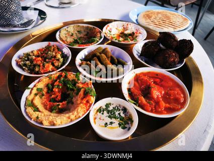 Stuzzichini mediorientali assortiti serviti in piccole ciotole su un grande vassoio rotondo Questa immagine rappresenta una cena condivisa e una gustosa cucina regionale. Foto Stock
