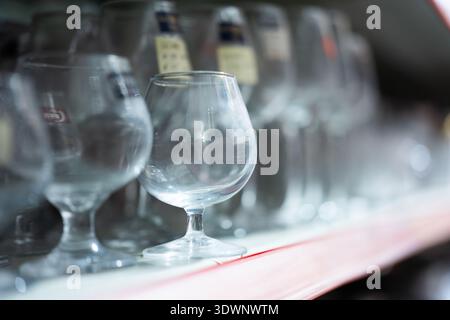 Cecchini di brandy chiari esposti sullo scaffale in un bar o in un negozio di liquori, illuminati delicatamente con una profondità bassa di Foto Stock