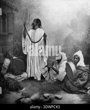 Questa fotografia antica della fine degli anni '1800 cattura un gruppo di incantatori di serpenti in Marocco, probabilmente Tangeri. Un uomo sta in piedi in modo prominente, tenendo un serpente in alto, mentre altri tre sono seduti, suonando un flauto e due tamburi a mano, creando una performance ritmica e affascinante. Foto Stock