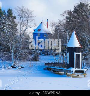 L'iconica Moomin House blu coperta di neve durante l'inverno a Moominworld, Naantali, Finlandia. Foto Stock