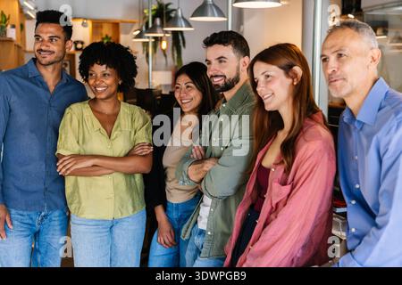 Team aziendale diversificato che collaborano sorridendo in ufficio Foto Stock