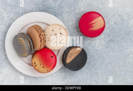 Biscotti assortiti di macaroon multicolore su sfondo grigio in cemento. Dolci macaron francesi. Deserto per buongustai. Messa a fuoco selettiva, t Foto Stock