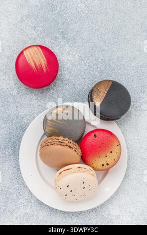 Biscotti assortiti di macaroon multicolore su sfondo grigio in cemento. Dolci macaron francesi. Deserto per buongustai. Messa a fuoco selettiva, t Foto Stock