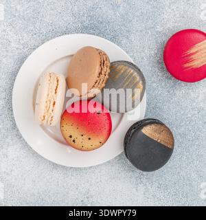 Biscotti assortiti di macaroon multicolore su sfondo grigio in cemento. Dolci macaron francesi. Deserto per buongustai. Messa a fuoco selettiva, t Foto Stock
