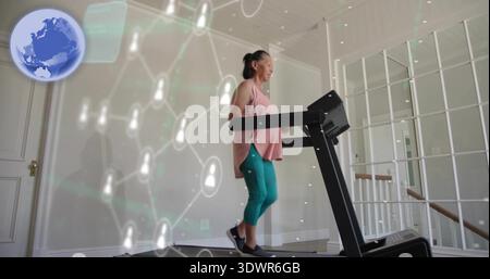 Donna asiatica che cammina indossando una tunica rosa sul tapis roulant a casa, sovrapposizione di rete, spazio per copiare Foto Stock