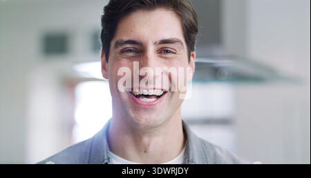 Sorridi, ritratto e uomo a casa, divertente per l'umorismo e la fiducia nel salotto. Appartamento, commedia e persona in salotto, felicità e calma con scherzo Foto Stock
