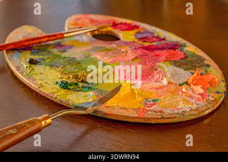 Strumenti di pittura e colorate vernici a olio su tavolozza di artisti in legno Foto Stock