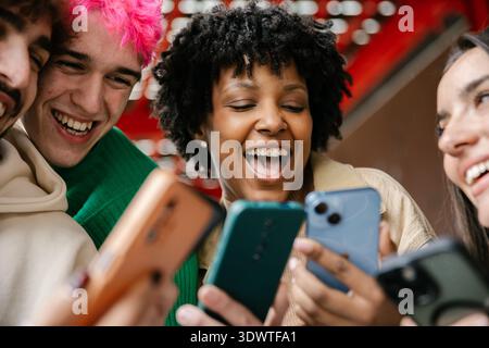 Gruppi diversi di amici che ridono insieme utilizzando gli smartphone all'aperto Foto Stock