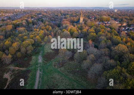 Immagine aerea della storica guglia della chiesa di San Paolo che si innalza dagli alberi d'autunno dorati di Kersal Moor, guardando verso l'orizzonte suburbano di Prestwich Foto Stock