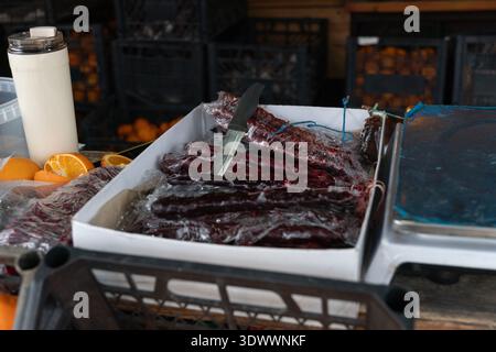 I tradizionali dolci churchkhela sono esposti sul bancone del mercato con confetture di uva e noci impilate, arance, coltelli e scaglie in Abkhazia. Marketing alimentare Foto Stock