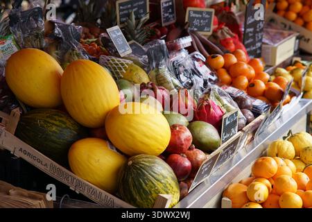 Colorato mercato della frutta traboccante di meloni, arance e frutti tropicali esotici. Mentone, Francia Foto Stock