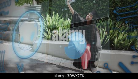Donna in posa laureata in berretto e abito, che solleva il telefono per selfie nel campus, HUD, spazio copia Foto Stock