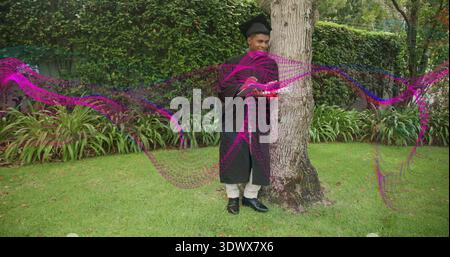 Uomo in piedi che indossa un abito graduato e un mensa accanto all'albero in giardino, con sovrapposizioni magenta Foto Stock