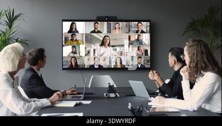 Un gruppo di uomini d'affari partecipa a una teleconferenza riunita nella sala riunioni Foto Stock