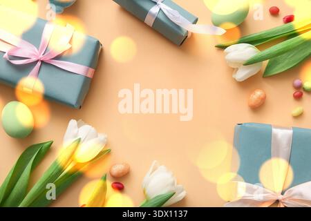 Cornice fatta di uova di Pasqua, splendidi fiori e confezioni regalo su sfondo colorato, vista dall'alto Foto Stock