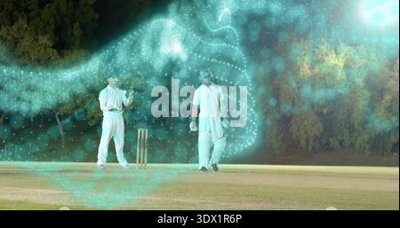 In piedi due cricket maschi che indossano tamponi bianchi e guanti vicino ai ceppi sul campo notturno, turbolenza di tè Foto Stock