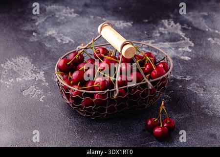 Ciliegie rosse dolci fresche nel cestello su fondo scuro, fuoco selettivo Foto Stock