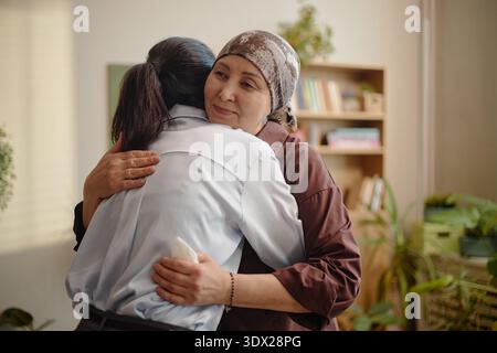 Donna asiatica di mezza età che conforta giovane donna adulta con abbraccio Foto Stock
