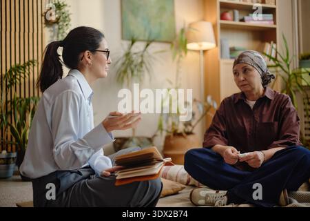 Donna caucasica di mezza età che coinvolge una donna anziana in una conversazione di supporto in casa Foto Stock