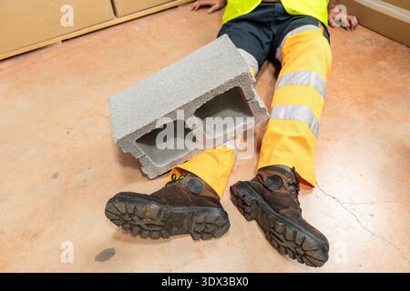 Un operaio edile è rimasto ferito in un incidente quando un mattone gli è caduto sulla gamba in un edificio in costruzione. Foto Stock