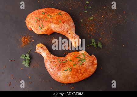 Marinato in salsa di pomodoro con erbe aromatiche e pepe cosce crude di pollo su fondo in pietra marrone. Cosce di pollo aromatizzate pronte per la cottura o la cottura alla griglia. Foto Stock