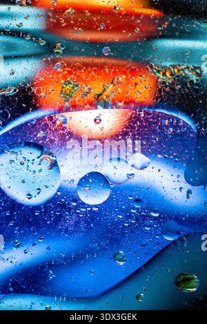 Sfondo astratto surreale con bollicine di olio blu e arancio su una superficie liquida per un look artistico moderno. Foto Stock
