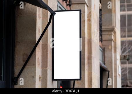 Cartello verticale vuoto appeso su un muro di pietra Foto Stock