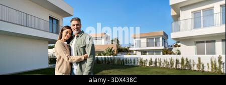 Ritratto dei proprietari di una coppia di famiglie felici e mature che si trovano fuori casa. Foto Stock