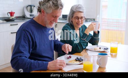 Una coppia anziana si diverte a fare colazione insieme in cucina Foto Stock