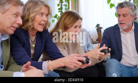 Amici anziani che gareggiano nei videogiochi e si divertono Foto Stock