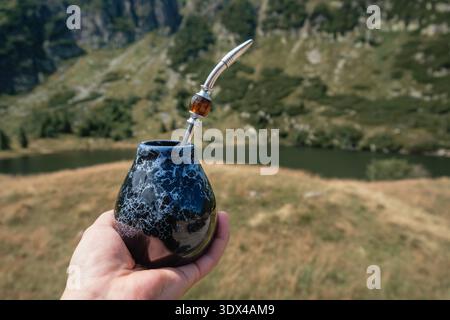 Rituale Yerba Mate all'aperto: Bombilla e Calabash in un paesaggio montano mozzafiato Foto Stock