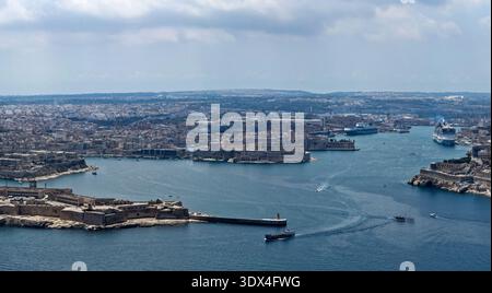 Vista ad alto angolo sul Porto grande di Maltas da Birgu, con il forte St Angelo e la penisola fortificata, navi da crociera e barche sull'acqua blu sotto le nuvole Foto Stock