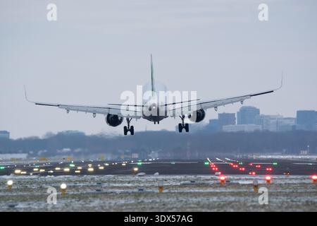 Vista da dietro di un aereo commerciale che atterra su una pista illuminata durante l'ora blu Foto Stock