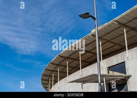 Un'immagine grandangolare che mostra il tetto curvo di un moderno edificio in pietra e un'alta lampada da strada. Foto Stock