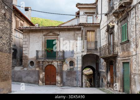 Vista prospettica di una strada nel borgo medievale di Scanno. L'immagine mostra antichi edifici in muratura con portali in legno e balconi in ferro battuto Foto Stock