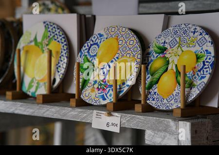 Piatti in ceramica dipinti a mano con motivi al limone su motivi blu-bianchi, esposti su cavalletti a €6,90 in un negozio di Mentone.Mentone, Francia Foto Stock