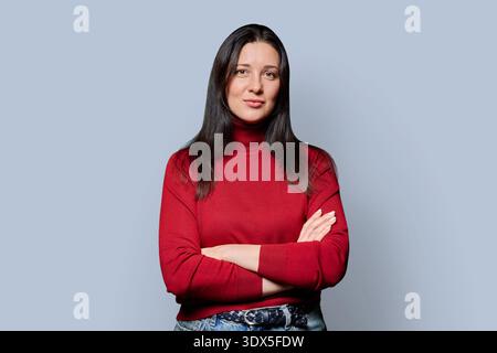 Ritratto di una bella donna sorridente di 40 anni che posa su sfondo grigio Foto Stock