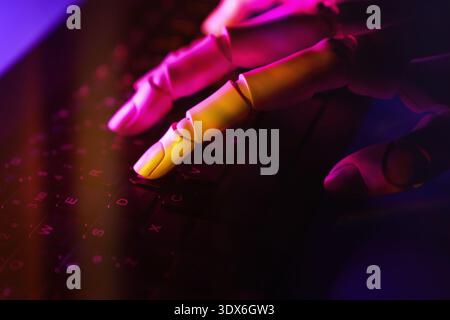 Immagine ravvicinata di una mano robotica che digita su una tastiera, illuminata da vivaci luci rosa e viola, a simboleggiare l'intelligenza artificiale avanzata A. Foto Stock