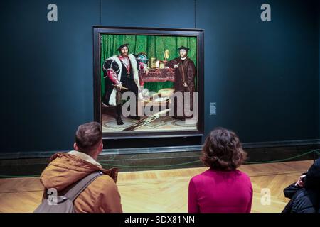 Londra, Regno Unito – visitatori che osservano "gli ambasciatori" di Holbein (1533) alla National Gallery, il ritratto famoso per il suo cranio anamorfico e il simbolismo Foto Stock