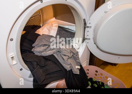cestino della biancheria con vestiti davanti al tamburo asciugatrice aperto Foto Stock