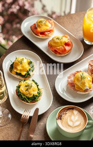 Un brunch gourmet con vari piatti a base di uova in camicia, tra cui uova reali con salmone, uova fiorentine con spinaci e il classico spirito Benedict Foto Stock