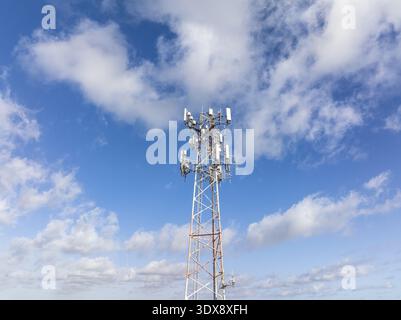 Veduta aerea di una torre di telefoni cellulari che si dirige verso il cielo sotto un cielo blu luminoso punteggiato da soffici nuvole bianche, Hollywood, Florida, United sta Foto Stock