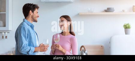 La coppia ama conversare mentre tiene un drink in un moderno ambiente da cucina durante il giorno Foto Stock