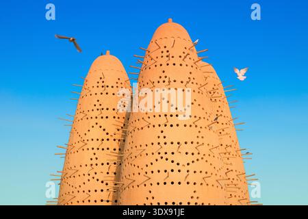 Torri di piccioni tradizionali nel Villaggio culturale di Katara, un centro culturale a Doha, Qatar. Gli uccelli volano e si appollaiano sulle antiche strutture Foto Stock