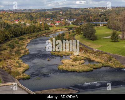 Un pittoresco fiume che si snoda attraverso un lussureggiante paesaggio autunnale con vegetazione vivace e case pittoresche Foto Stock