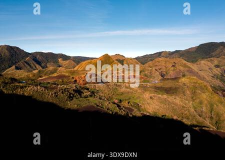 Vista aerea delle colline baciate dal sole, dove la luce dorata bagna il terreno accidentato con tonalità calde, creando un contrasto incredibile con le ombre profonde, Foto Stock