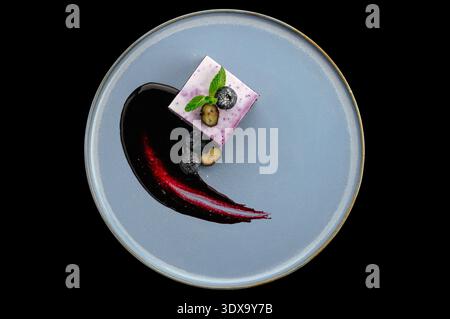 dessert ai mirtilli su un piatto con frutti di bosco e decorazioni Foto Stock