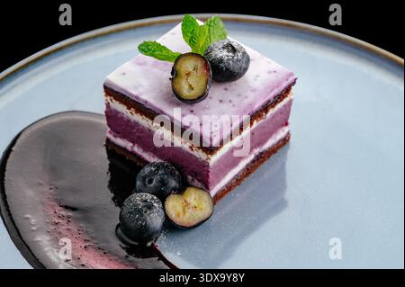 dessert ai mirtilli su un piatto con frutti di bosco e decorazioni Foto Stock